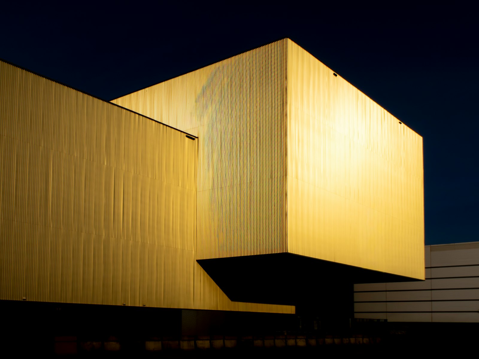 A gold-lit modern building against a dark night sky
