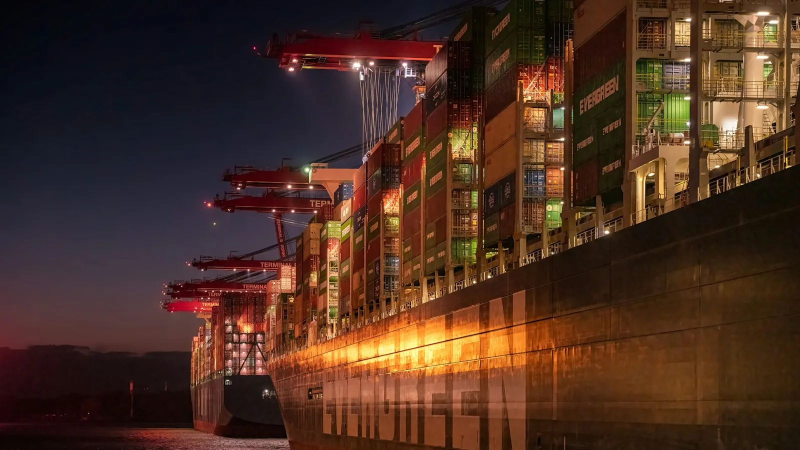 Container ship being loaded at a port terminal at dusk
